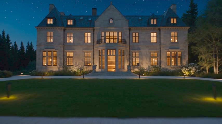 A grand country house lit up at dusk